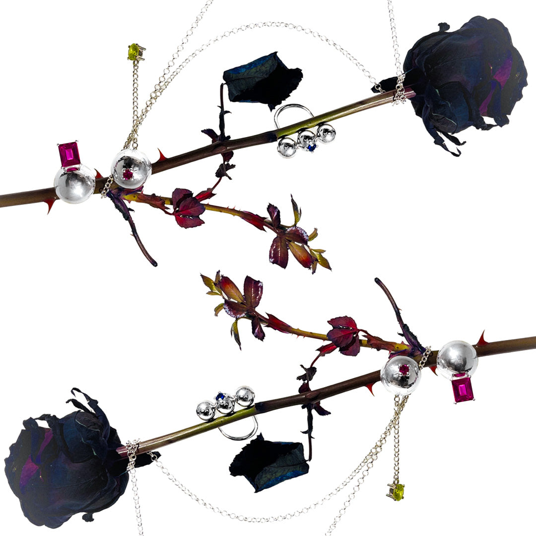 Jewelry set with black roses, pearls, and gemstones on a white background