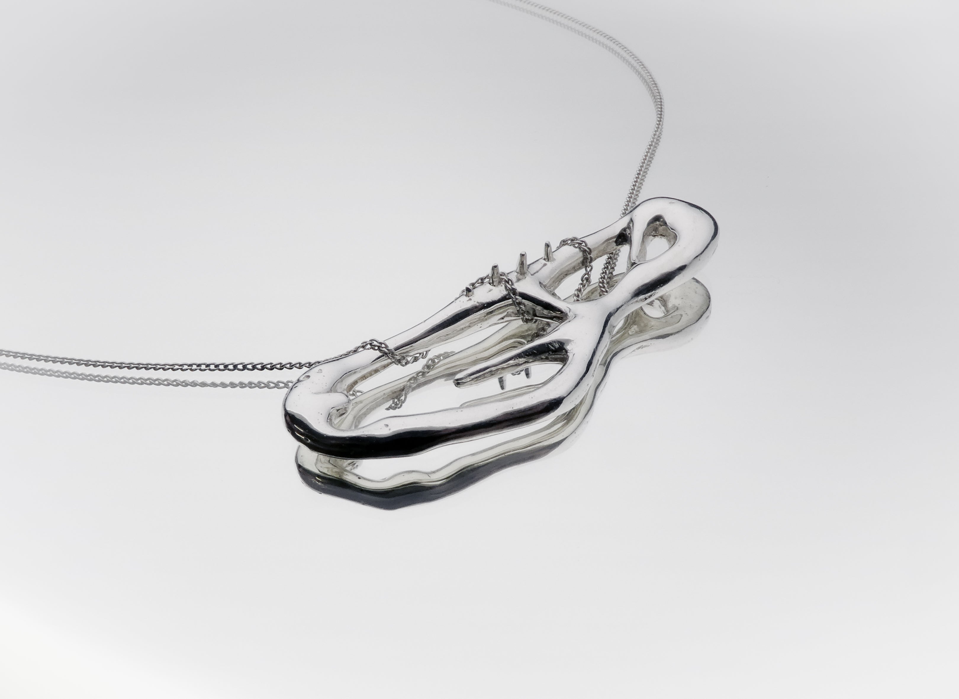 Silver necklace with a unique pendant on a light gray background liquid design