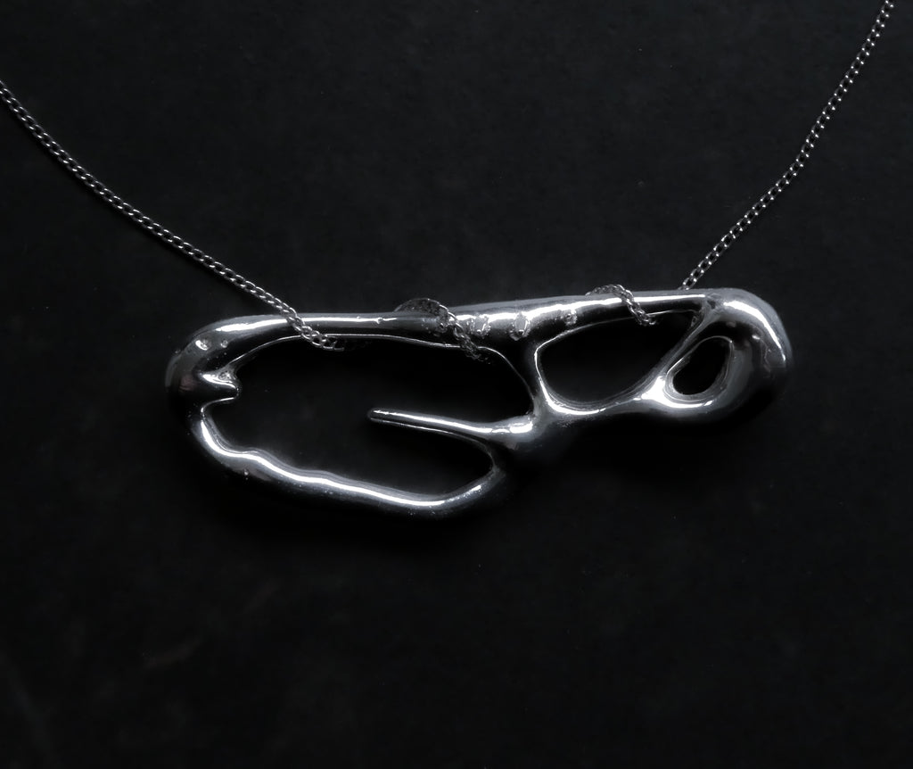 Silver pendant on a dark background liquid shape